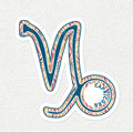 A die-cut vinyl sticker of the Capricorn zodiac symbol, featuring a colorful retro pattern in teal, orange, pink, and beige on a white background, displayed on a light gray textured surface.