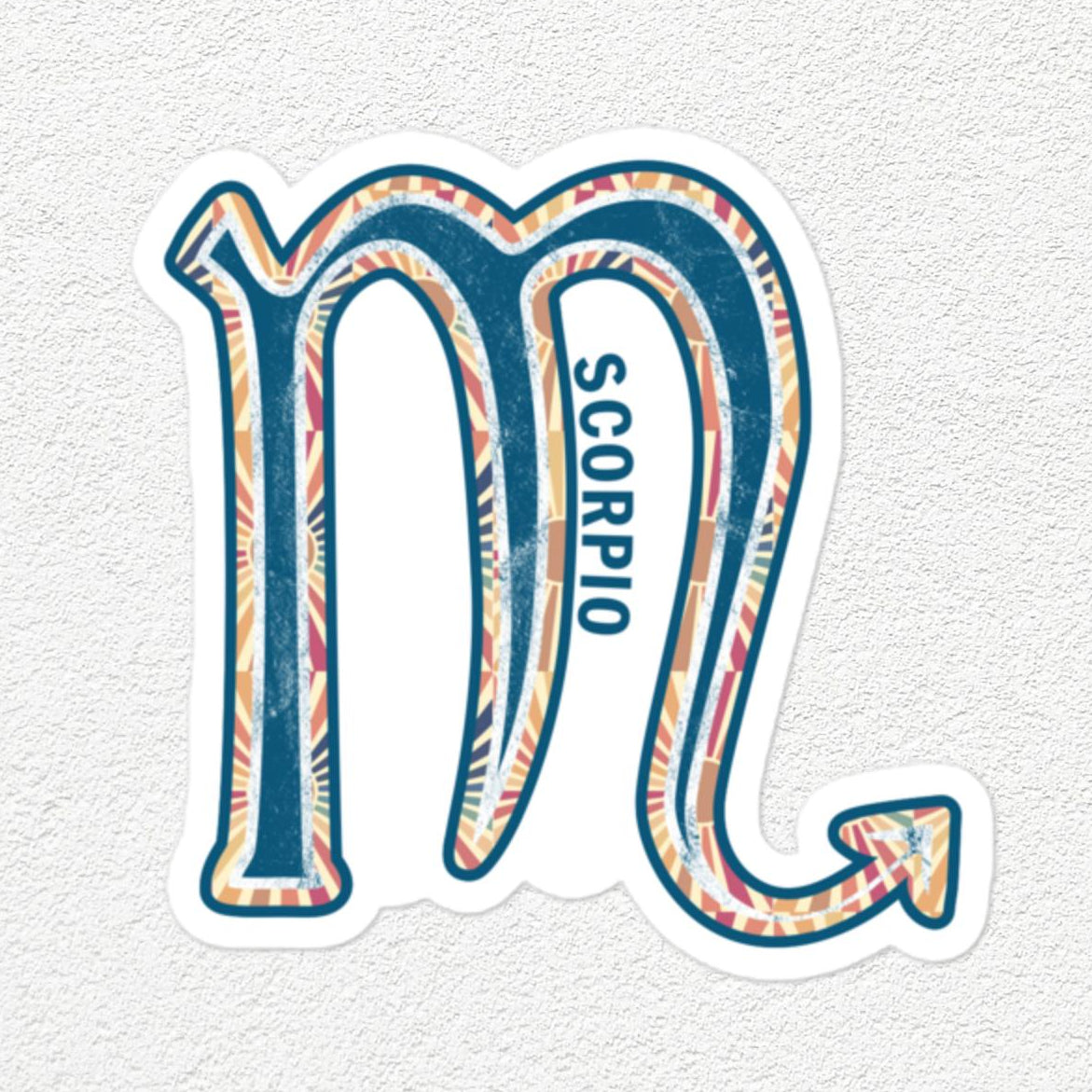 A die-cut vinyl sticker of the Scorpio zodiac symbol, featuring a blue and pink patterned design with the word 'SCORPIO' printed vertically, shown on a textured off-white background.
