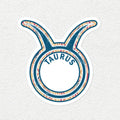 A die-cut vinyl sticker of the Taurus zodiac sign, featuring a blue and white patterned design with the word 'TAURUS' in blue text on a white circular background, set against a textured off-white wall.