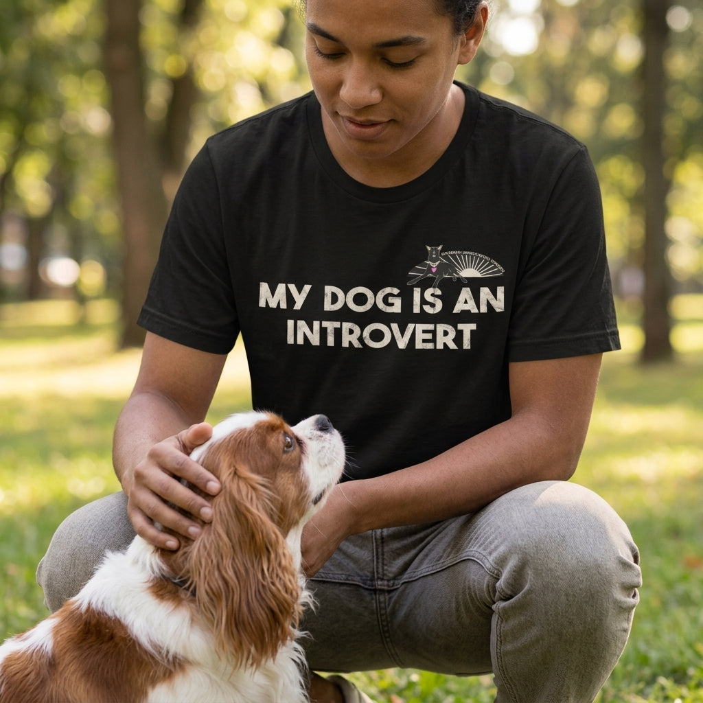 Person wearing a black t-shirt with 'My dog is an introvert' text, petting a dog in a park.